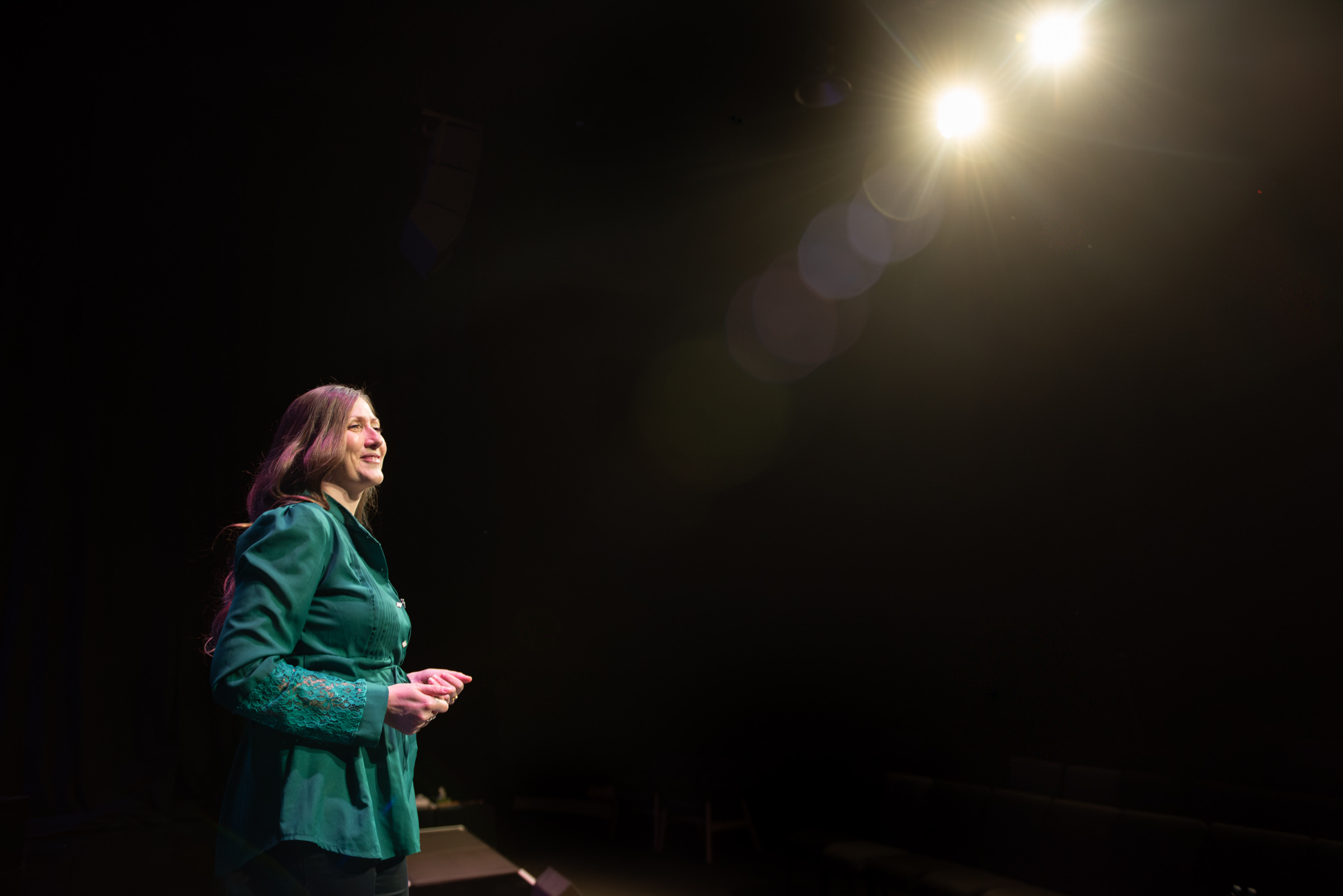 Audrey Muliva speaking on stage beneath a spotlight