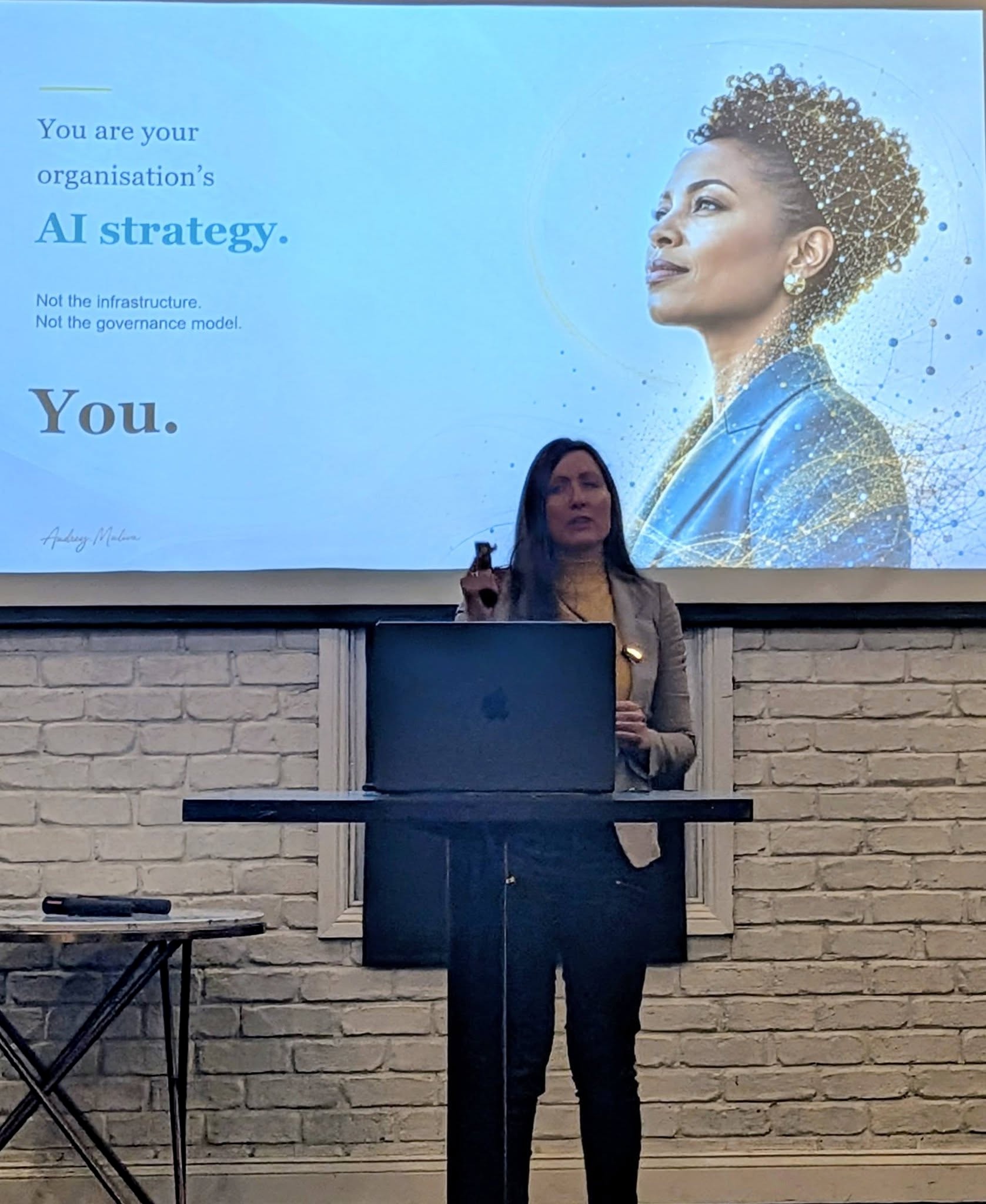 Audrey Muliva speaking in front of a presentation about AI strategy